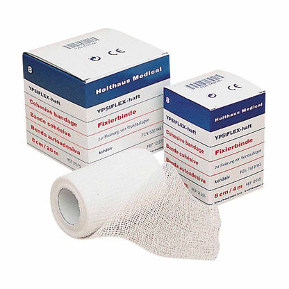 Haft-Mullbinde YPSIFLEX® haftend: hellgraue Mullbinde auf Rolle, zusammen mit Packung