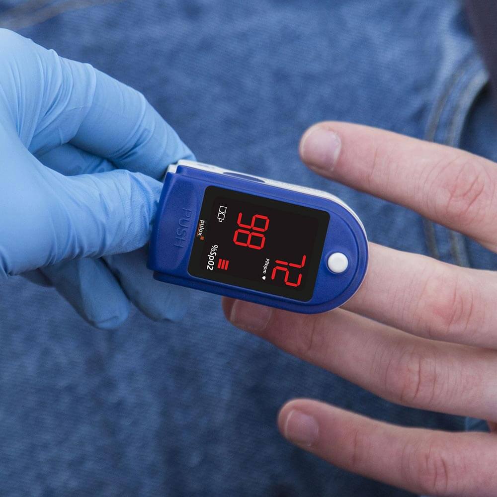 Finger-Pulsoximeter am Finger mit rotem LED-Display und Messwerten
