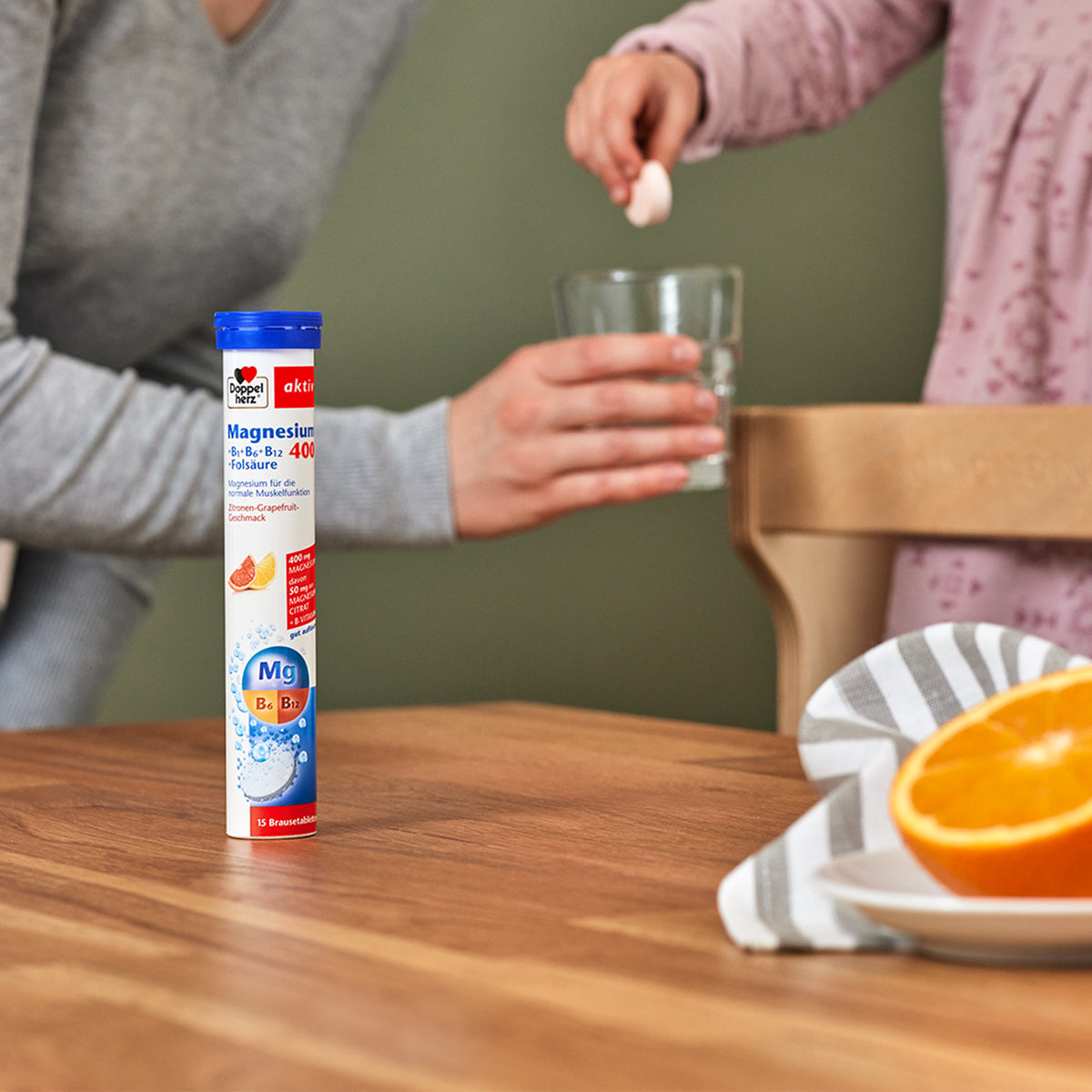 Doppelherz aktiv Magnesium 400 Brausetabletten-Röhrchen neben einem Glas