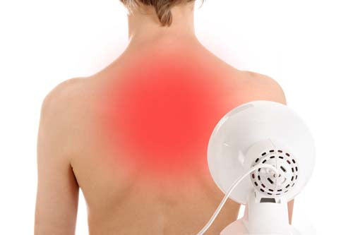 Using a red light lamp for heat therapy on tense areas of the body