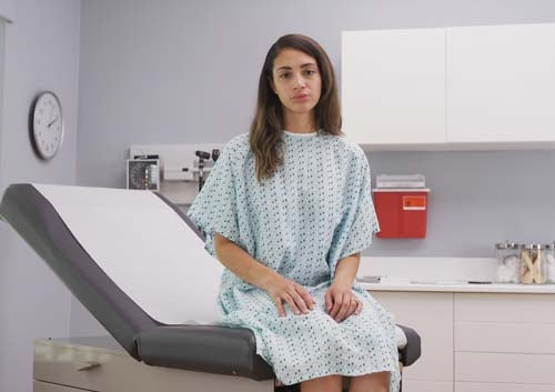 Una paciente está sentada en una camilla de tratamiento con crepé médico