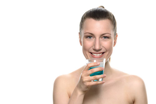Mujer con un vaso de enjuague bucal